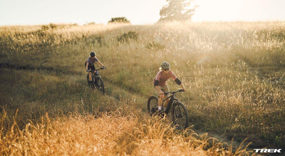 two people riding mountain bikes on a trail